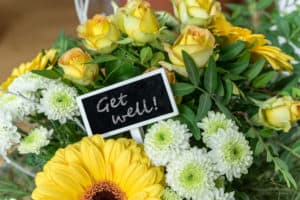 Bouquet of yellow and white roses, gerberas, chrysanthemums and a small board with English text: get well soon